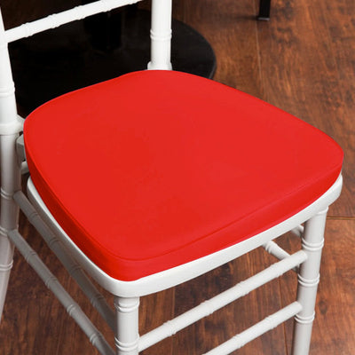 Red chair cushion on a white chair in a wooden setting.
