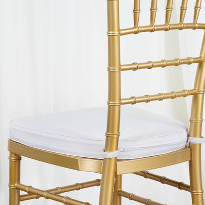 Gold chiavari chair with white cushion on a plain backdrop.