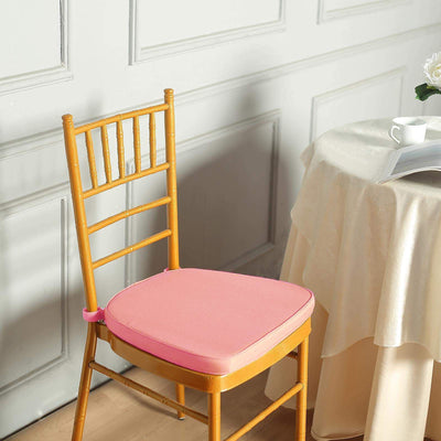 Pink chair cushion on a wooden chair beside a table with a magazine.