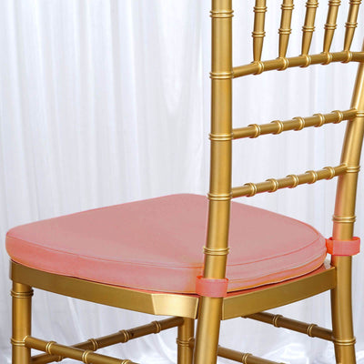 Gold chiavari chair with a pink cushion on a white backdrop.