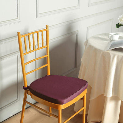 Purple chair cushion on a wooden chair beside a table with a cup and magazine.