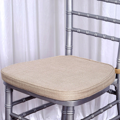 Silver chiavari chair with beige cushion on a draped background.