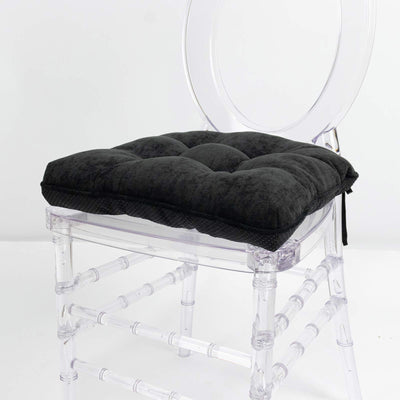 Black tufted chair cushion on a clear acrylic Chiavari chair