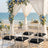 Beach wedding ceremony setup with floral arch and white chairs by the ocean