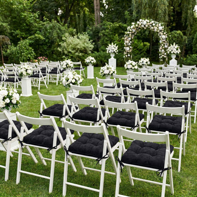 Outdoor wedding ceremony setup with white chairs and floral arch in garden