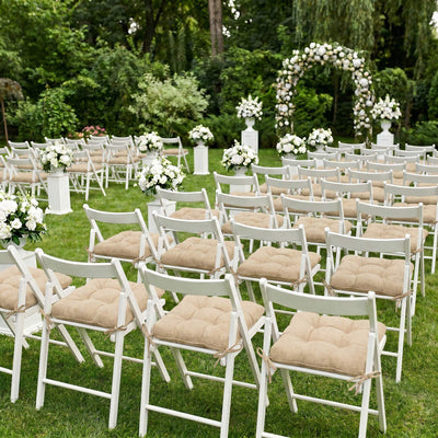 Outdoor wedding ceremony seating with white chairs and floral arch in garden setting