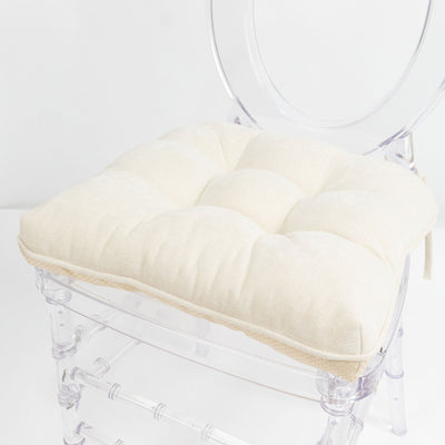 Cream tufted cushion on clear acrylic chair, minimal white interior decor