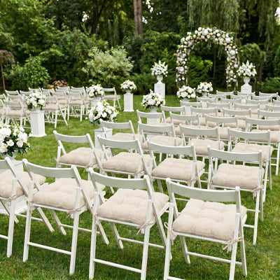 Outdoor garden wedding ceremony setup with white chairs and floral arch