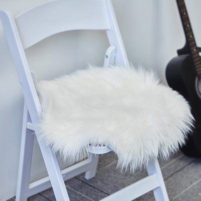 Fluffy white chair cushion on a folding chair with a guitar in the background.