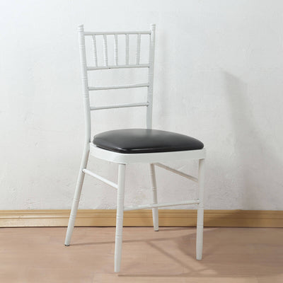 White chiavari chair with black cushion on a light wooden floor.