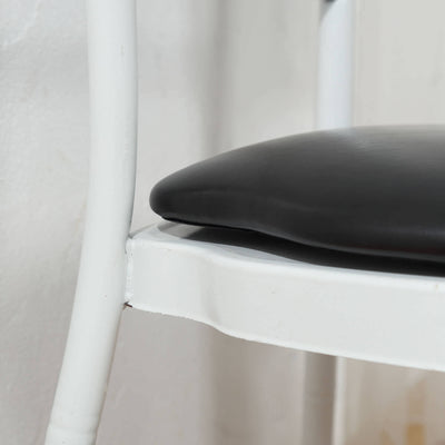 Black cushioned chair seat on a white metal frame.