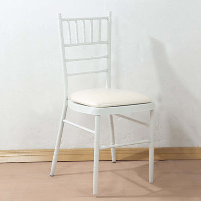 White chiavari chair with beige cushion on a plain backdrop.