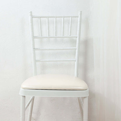 White chiavari chair with cream cushion on a plain backdrop.
