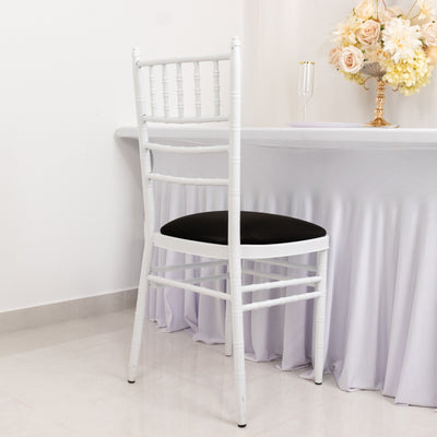 White chiavari chair with black cushion against a table setting.