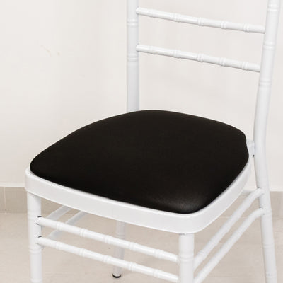 White wooden chair with a black cushioned seat against a plain background.