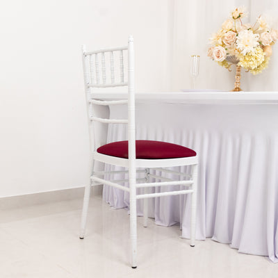 White chair with a burgundy seat at an elegantly set table.