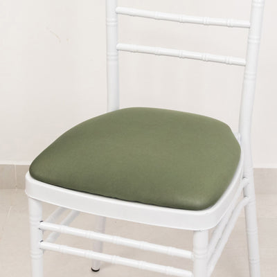 White chair with green cushion on a plain backdrop.