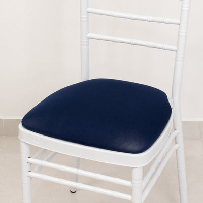 White chiavari chair with navy cushion on a plain background.