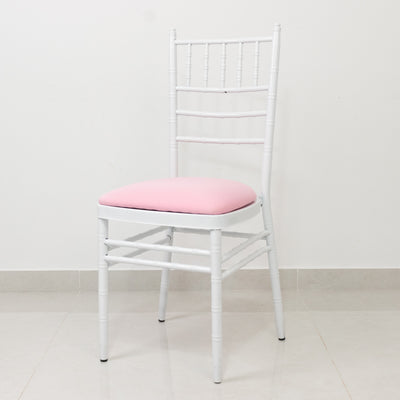 White chiavari chair with pink cushion on a plain background