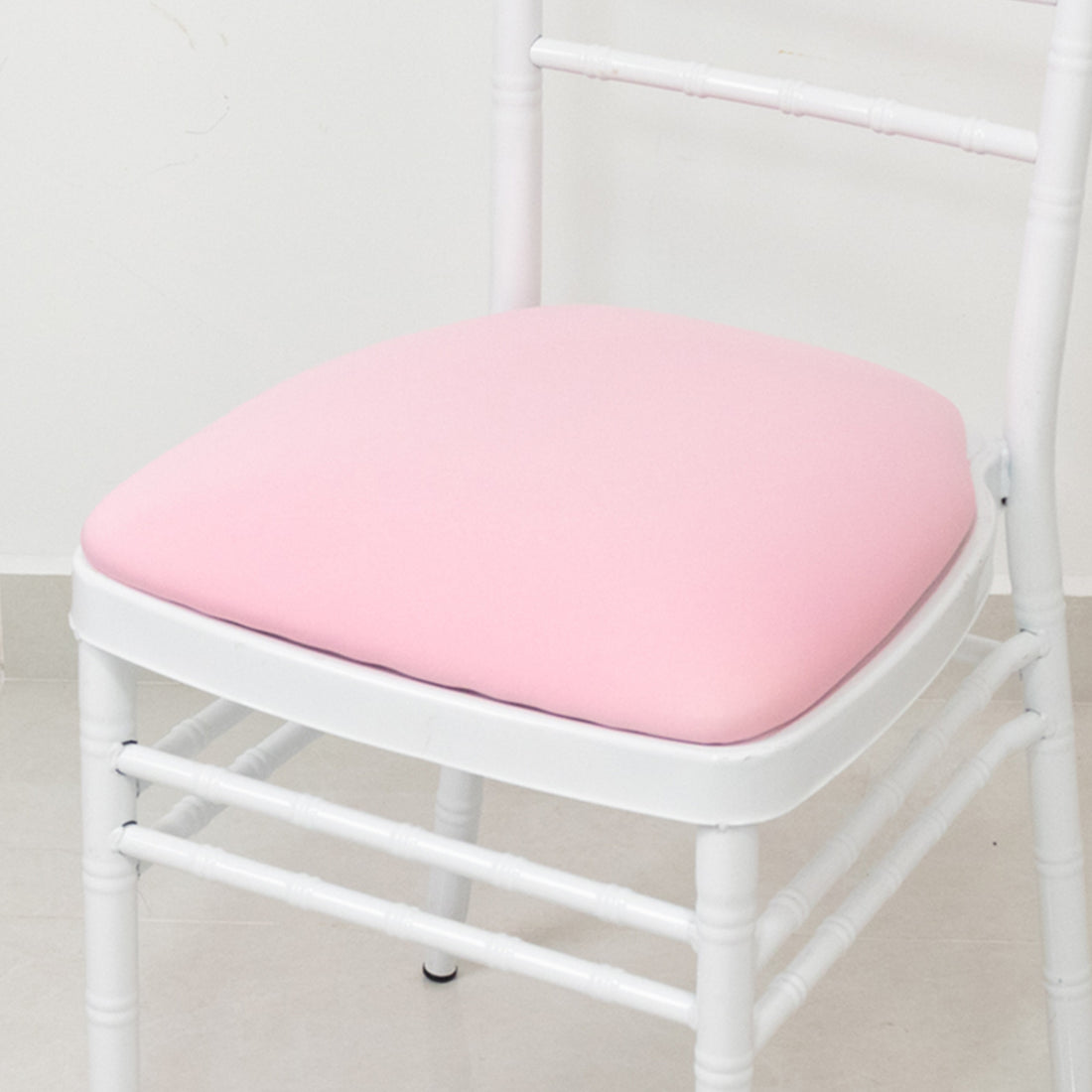 White chair with pink cushion on a plain background.