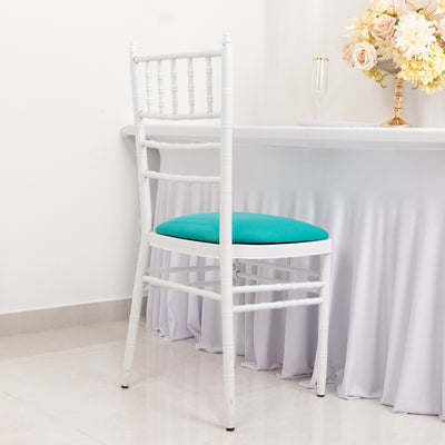 White chiavari chair with teal cushion against a light backdrop.