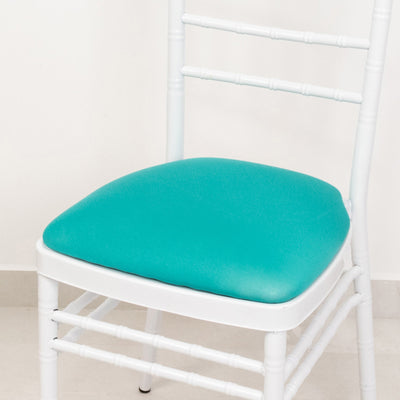 White chair with turquoise cushion on a plain background.