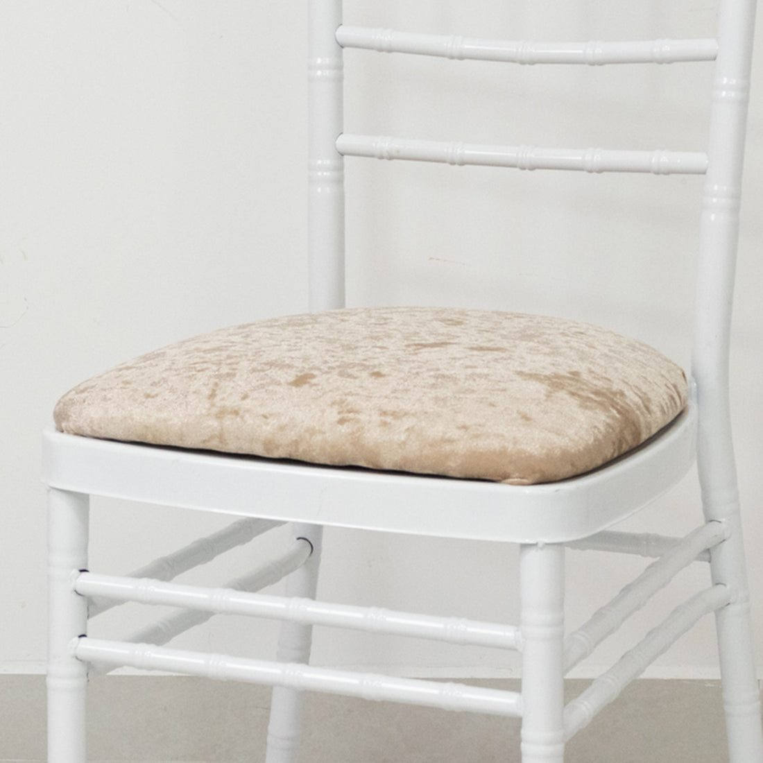 White chair with plush beige cushion on a plain background.