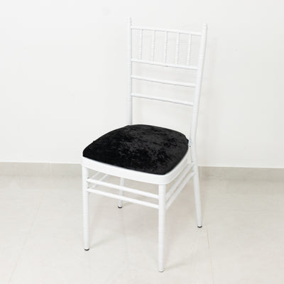 White chiavari chair with black cushion on a plain background