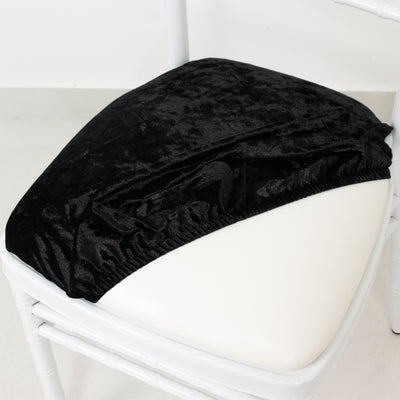 Black velvet chair cover on a white chair in a studio setting.