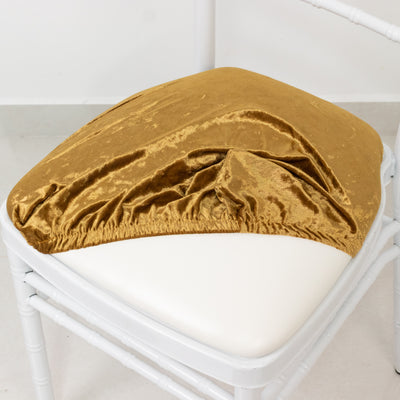 Gold velvet chair cover on a white chair in a studio setting.