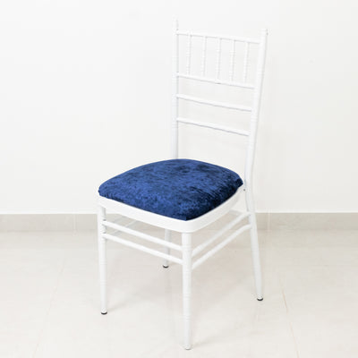 White chiavari chair with a blue velvet cushion on a plain background.