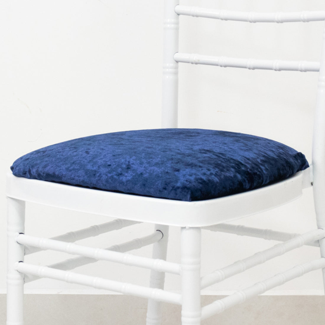 Navy blue velvet chair cushion on a white chair
