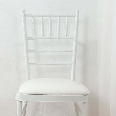 White chiavari chair with a padded seat on a plain background