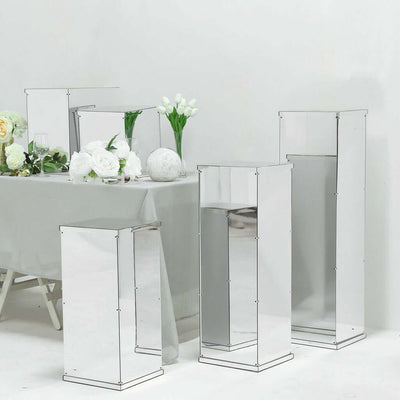 Mirrored display pedestals in various sizes arranged with floral decor.