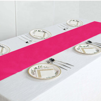Pink table runner on a white table set with elegant plates and cutlery.