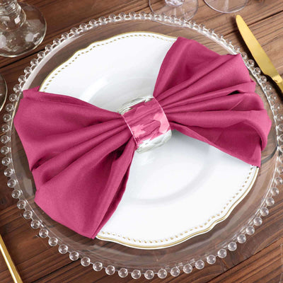 Elegant magenta napkin tied with a silver ring on a decorative plate.