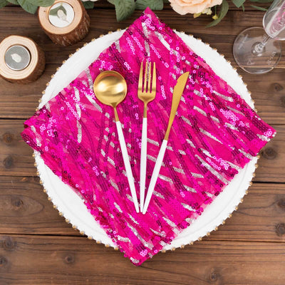 Gold cutlery on a vibrant pink sequin napkin atop a white plate