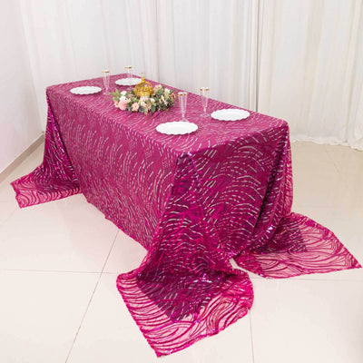 Elegant pink patterned tablecloth draped over a table with decorative items.