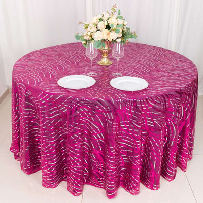 Round pink patterned tablecloth with plates and floral centerpiece.