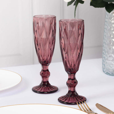 Set of two elegant purple glass champagne flutes on a table.