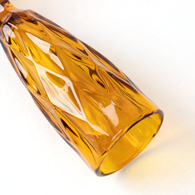 Amber glass champagne flute with a textured diamond pattern.