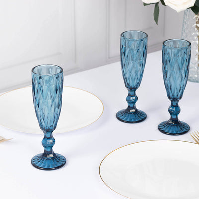 Elegant blue crystal champagne flutes on a dining table.