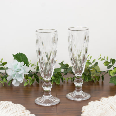 Set of two elegant crystal champagne flutes on a wooden table.