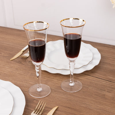 Elegant champagne flutes with gold rims on a wooden table setting.
