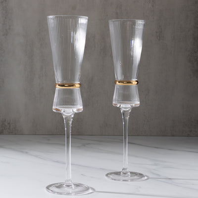 Elegant ribbed champagne flutes with gold accents on a marble surface.