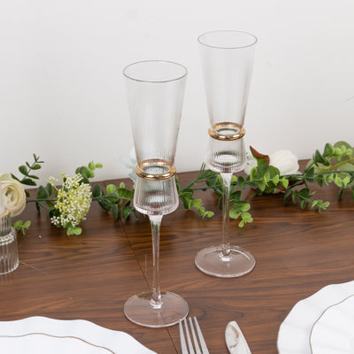 Elegant champagne flutes with gold accents on a dining table setting.