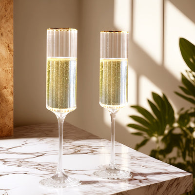 Elegant champagne flutes with gold accents on a marble surface.