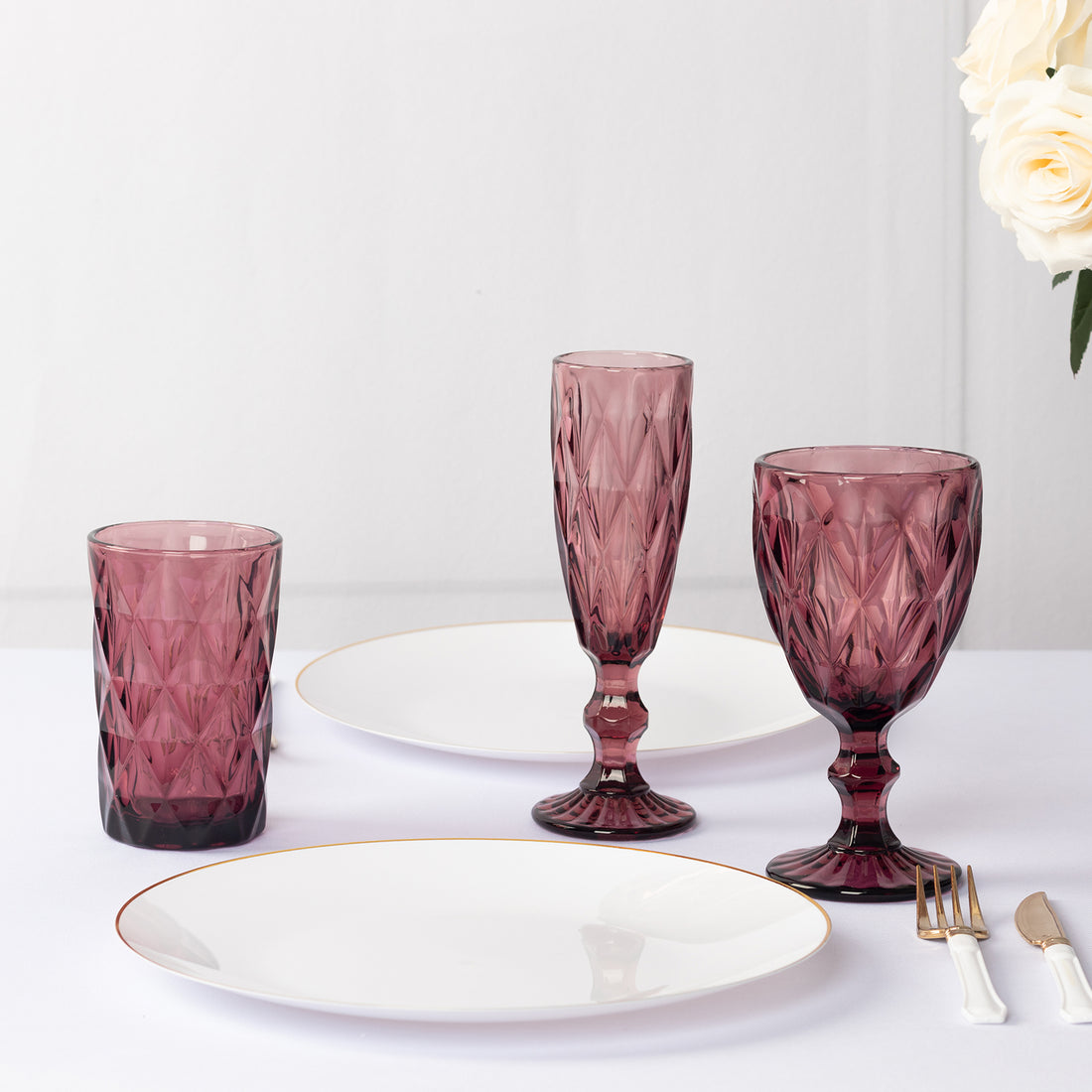 Set of elegant purple glassware and white plates on a table.
