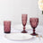 Set of elegant purple glassware and white plates on a table.