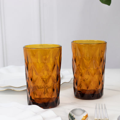 Amber glass tumblers with a diamond pattern on a marble surface.